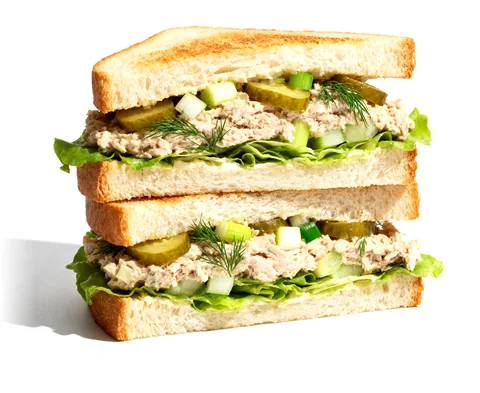 A tuna club sandwich cut in two and stacked: golden toast, tuna salad with pickles and dill, lettuce.